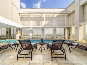 a large building with a pool and chairs and a swimming pool at VM Flats Guarulhos Aeroporto in Guarulhos