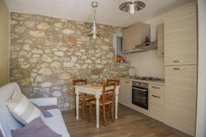 a kitchen with a table and chairs and a stone wall at Podere il Gallo Agriturismo in Campiglia Marittima