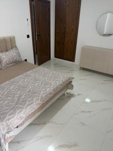 a bedroom with a bed and a tiled floor at Lux appartement S plus deux a hay el wahat in El Aouina Station