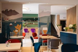 ein Restaurant mit farbenfrohen Stühlen und Tischen und einer Bar in der Unterkunft Vitalé Hotel Daniela in Levico Terme