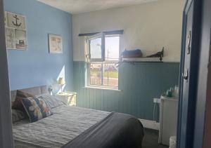 a blue bedroom with a bed and a window at Henry's On The Prom in Great Yarmouth