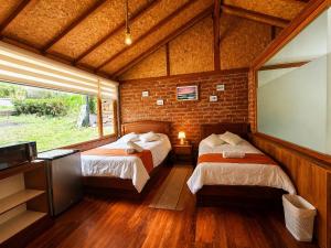ein Schlafzimmer mit zwei Betten und einer Ziegelwand in der Unterkunft Munay Wasi by Hospedaje Puntzán in Baños