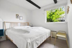 a white bedroom with a bed and a window at 40583-Juelsminde-Pot-Strandby-119 in Sønderby