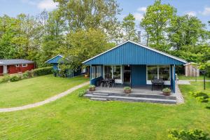 a blue cottage with a deck in a yard at 40583-Juelsminde-Pot-Strandby-119 in Sønderby