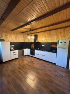a large kitchen with white appliances and a wooden ceiling at Bergblick in Arpaşu de Sus