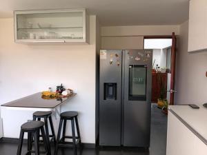 a kitchen with a refrigerator and a counter with stools at Casa Munay in Huancayo
