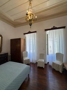 a bedroom with a bed and two chairs and a chandelier at Marthas Traditional House in Symi