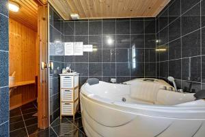 a large white tub in a bathroom with black tiles at C11769-Hemmet-Vester-Faelled-14 in Falen +35 photos