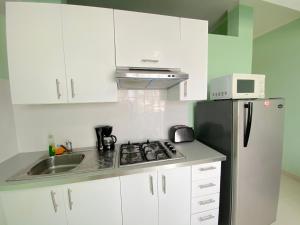 a kitchen with white cabinets and a black refrigerator at AVENTURA SUITES playa LOS CORALES - great location! in Punta Cana