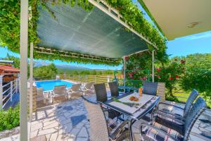 a patio with a table and chairs and a pool at Villa with pool near Split in Krušvar