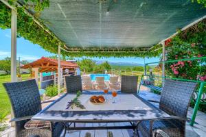 a table and chairs on a patio with a pergola at Villa with pool near Split in Krušvar