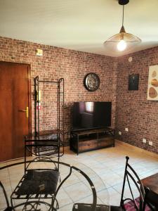 a living room with a television and a brick wall at La Chambres des Secrets in Vierzon