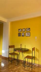 a table and chairs in a room with a yellow wall at Aqui y Ahora in Pisac +33 photos