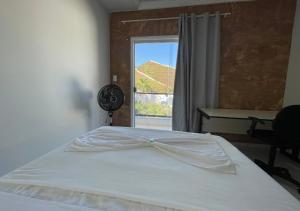 a bedroom with a white bed with a window at 474 Flats e Suítes Standard in Ipatinga