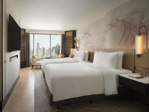 two beds in a hotel room with a view at Fairmont Bangkok Sukhumvit in Bangkok