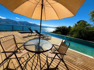 a table and chairs with an umbrella on a deck at Casa Gaia GuestHouse in Ilhabela