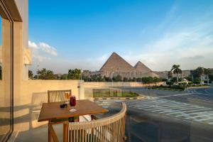 a table on a balcony with a view of pyramids at Koun Pyramids Hotel in Cairo