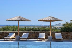 a group of chairs and umbrellas next to a swimming pool at Agnadi Hotel in Agia Anna Naxos