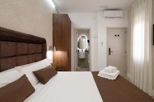 a bedroom with a large white bed and a bathroom at Rosales Suites in Madrid
