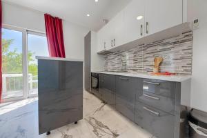 a kitchen with gray cabinets and a brick wall at MEMO's DUKAT in Šušanj