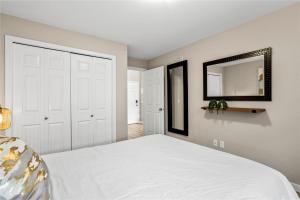 a bedroom with a white bed and a mirror at Pool-View condo at Pinnacle Pointe Resort-Sleeps 6 in Kelowna