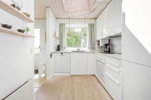 a kitchen with white cabinets and a wooden floor at FY132-Middelfart-Stjernevej-109 in Middelfart