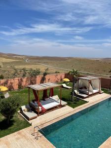 a swimming pool with two chairs and a gazebo at Villa Alaīa avec vue panoramique et piscine sans vis à vis - Marrakech in Marrakesh