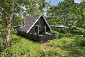 a black cabin in the middle of a forest at 1105-ringkobing-Fyrrealle-20 in Nørby