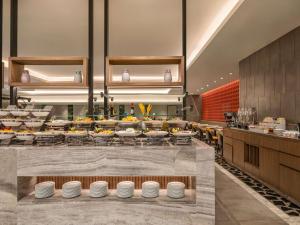 a restaurant with a buffet line with food at Movenpick Hotel & Residences Hajar Tower Makkah in Mecca