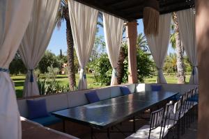 a table and chairs in a patio with curtains at Domaine 3 Riads in Marrakesh +126 photos