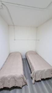 two beds in a room with white walls at Hermosos monoambientes a estrenar in Comodoro Rivadavia