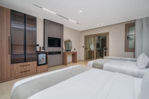 a bedroom with two beds and a flat screen tv at Koun Pyramids Hotel in Cairo