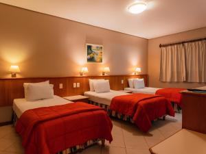 a hotel room with three beds with red blankets at Marcopolo Suites Iguazu in Puerto Iguazú +62 photos