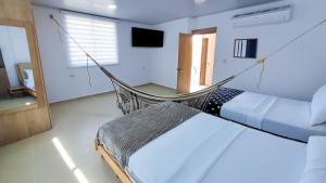 a hammock in a room with a bed and a television at Casa Daguer Beach House in Cartagena de Indias