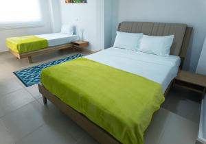 a bedroom with a bed with a green blanket on it at Casa Daguer Beach House in Cartagena de Indias