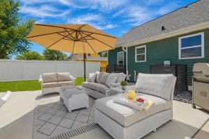 a patio with two chairs and an umbrella at Lambeau View Pool Rooftop Entertainment Room in Green Bay +42 photos