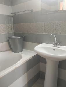 a white bathroom with a sink and a bath tub at Morgan Appartements in Hammam Sousse