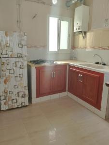 a kitchen with red cabinets and a sink and a window at Morgan Appartements in Hammam Sousse