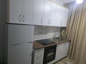 a small kitchen with white cabinets and a sink at Solei Sea Apartment in Shëngjin