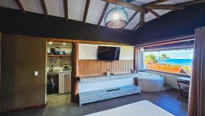 a living room with a television and a kitchen with a tub at Studio Moderno com Vista pro mar com hidromassagem e churrasqueira privativas e Piscina aquecida na área comum in São Sebastião