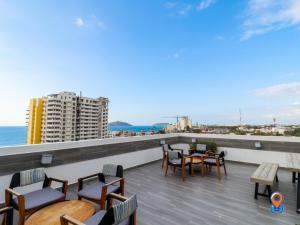 a balcony with tables and chairs and a view of the ocean at Depa Amplio Vista al Mar Cerca del Malecón in Mazatlán