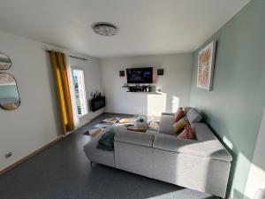 a living room with a couch and a tv at Bel Appartement Perrières in Brive-la-Gaillarde