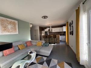 a living room with a couch and a kitchen at Bel Appartement Perrières in Brive-la-Gaillarde