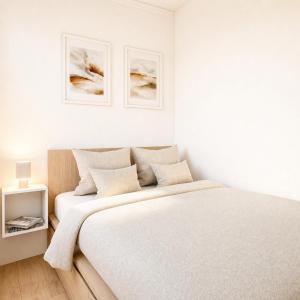 a white bedroom with two beds and two pictures on the wall at Express Guest House in Klaipėda