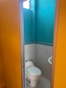 a bathroom with a white toilet and a blue wall at Pacasmagic Surf&Kite in Pacasmayo