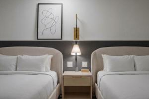 ein Hotelzimmer mit zwei Betten und einem Tisch mit Lampe in der Unterkunft Hotel Longmont in Longmont + 7 Fotos