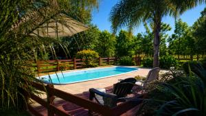 a swimming pool with two chairs and an umbrella at Cabañas Pulmahue in Colón