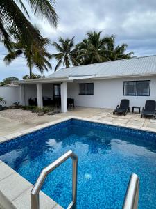 a swimming pool in front of a house at Hildas Villa in Arorangi