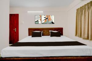a bedroom with a large bed with a red door at HOTEL O KB LODGING ROOMS in Itwāri