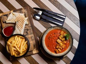 a table with a bowl of soup and french fries at TRIBE Riga City Centre - Renovated 2026 in Riga